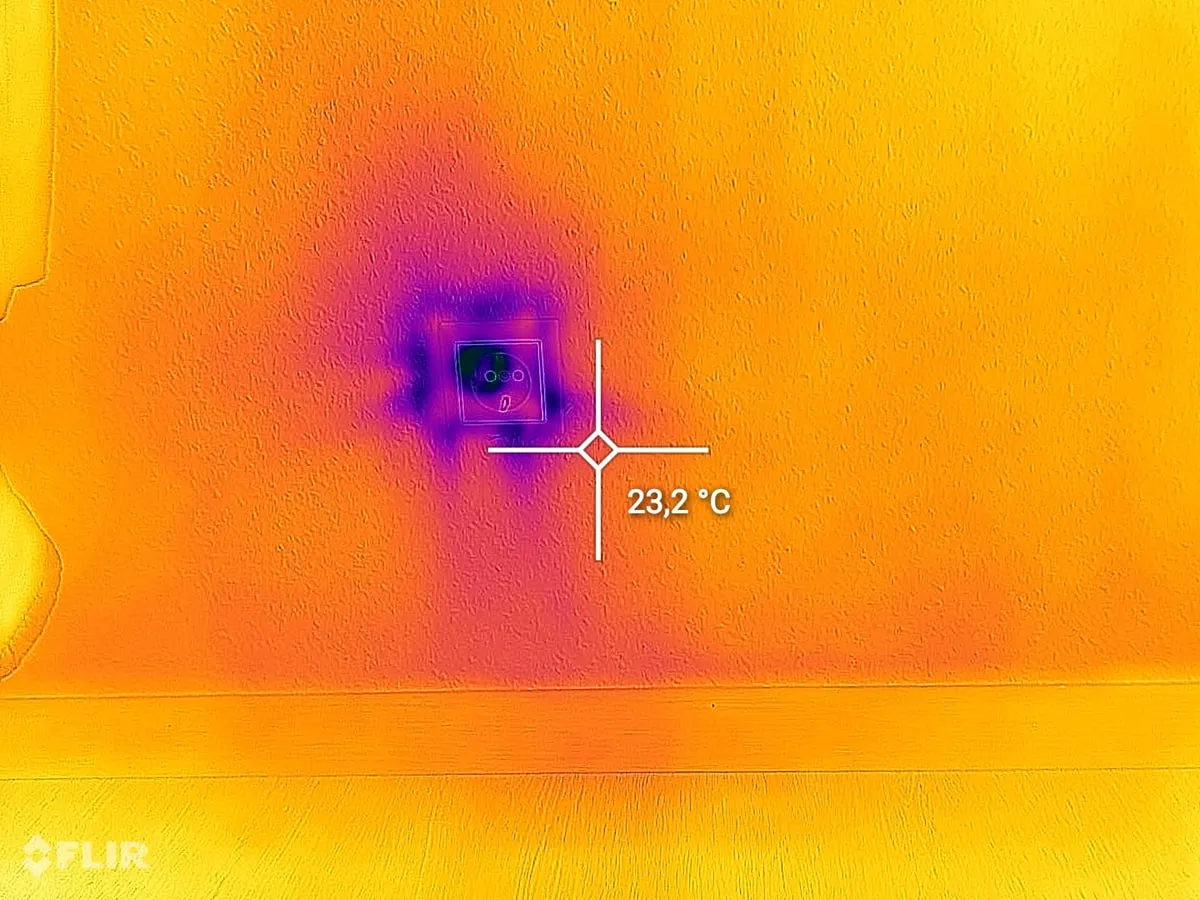 Thermografie-Aufnahme einer Steckdose in einer Innenwand: die deutlich kühlere Zone rund um die Dose weist auf eindringende Kaltluft hin